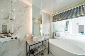 釜山De Homme Hotel的白色的浴室设有浴缸、水槽和浴缸。