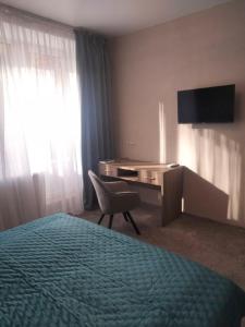 切尔尼戈夫Hotel Prydesnyansky的酒店客房配有一张床、一张书桌和一台电视。