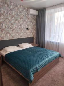 切尔尼戈夫Hotel Prydesnyansky的一间卧室配有一张带蓝色毯子的床和窗户。
