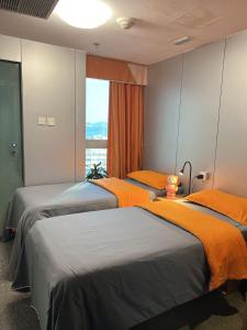 香港香港奥斯酒店的带窗户的客房内的两张床