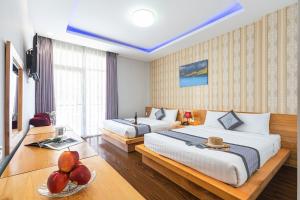 大叻Dalat Wind Hotel的酒店客房设有两张床和一张带一碗水果的桌子。