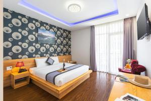 大叻Dalat Wind Hotel的一间卧室设有一张大床和一个带板的墙壁