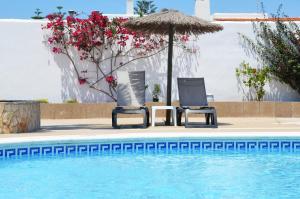 圣安东尼奥湾Hotel Apartamentos Vibra San Marino的游泳池旁的两把椅子和一把遮阳伞
