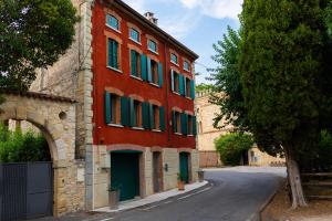 Marano di ValpolicellaMaregnago Relais的街道上一座红色的建筑,设有绿色百叶窗