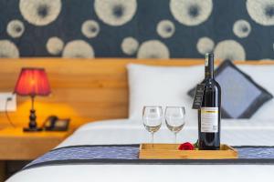 大叻Dalat Wind Hotel的床上有一瓶葡萄酒和两杯酒