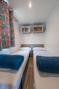 帕尔斯Albatross Mobile Homes on Camping Playa Brava的带3张床和蓝色枕头的客房