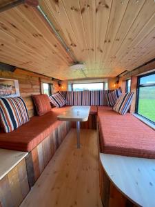 IrvinestownSleeps 18 Double Decker Bus Hot Tub Sauna Cinema Pets的一辆火车车厢,车上设有长椅和桌子