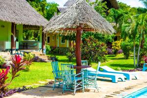 迪亚尼海滩Oasis Diani Beach Villas的庭院配有桌椅和遮阳伞