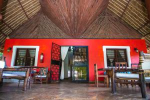 迪亚尼海滩Oasis Diani Beach Villas的一间设有红色墙壁和桌椅的房间