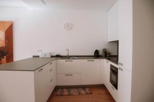 卡米尼亚Just Like Home - Casinhas da Vila T2 em Caminha的厨房铺有木地板,配有白色橱柜。