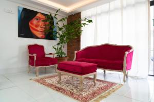 卡宴Hôtel Amazonia Cayenne Centre的客厅配有两把椅子和一张红色沙发