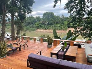 琅勃拉邦占城河景月光酒店的甲板上设有沙发和桌子,享有河景