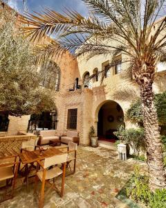 托泽尔Dar Tozeur的一座建筑前的庭院,庭院里设有桌子和棕榈树