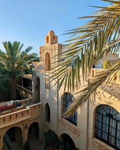 托泽尔Dar Tozeur的一座带钟楼和棕榈树的建筑