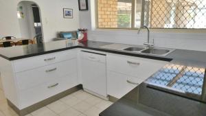 扬巴25 Admiralty Court, Yamba的厨房配有白色橱柜和水槽