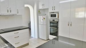 扬巴25 Admiralty Court, Yamba的白色的厨房配有冰箱和微波炉。