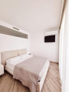 西尔米奥奈Appartamento ORCHIDEA a Sirmione sul Lago di Garda con piscina, giardino e spiaggia con molo的白色卧室设有一张大床和电视。