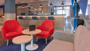 柏林柏灵城中心假日酒店的大堂设有红色的桌椅和酒吧。