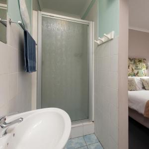 兰伯特湾Albatross Accommodation的带淋浴和盥洗盆的浴室以及1张床。