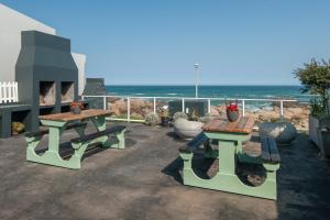 兰伯特湾Albatross Accommodation的一个带两张野餐桌的庭院和大海