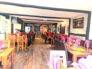 兰彼得The Black Lion Royal Hotel的餐厅设有木桌、椅子和粉红色餐巾