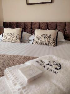 兰彼得The Black Lion Royal Hotel的一张带白色床单和枕头的床,上面有横隔