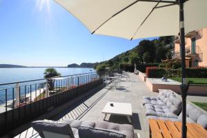 梅纳Resort Antico Verbano的一个带沙发和桌子及遮阳伞的庭院