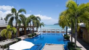 拉威海滩Selina Serenity Rawai Phuket的一座棕榈树和海洋的无边游泳池