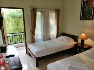 日惹Puri Pangeran Hotel的一间卧室设有两张床和大窗户