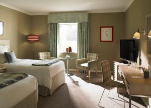 奇切斯特古德伍德酒店 的一间卧室配有两张床、一张桌子和一台电视。