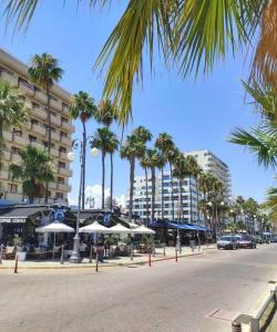 拉纳卡Extremely comfy 10min walk to Beach & Town的一条种有棕榈树和遮阳伞的街道和一座建筑