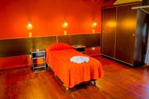 梅洛Hotel Villa Sol的红色的房间,配有一张带橙色毯子的床