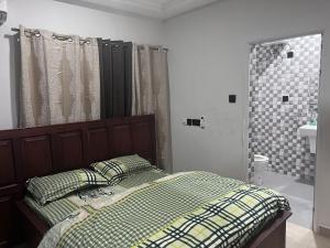 阿克拉T-Roys Apartments的一间卧室配有一张床,浴室设有淋浴。
