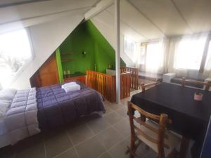 圣卡洛斯-德巴里洛切Cinerama Hostel的一间卧室设有一张床铺和一张桌子,还有一面绿色的墙壁