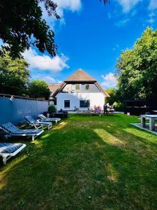 德科赫The island life Texel - Wellness的楼前草坪上的一组躺椅