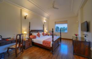 萨瓦伊马多普尔WelcomHeritage Mount Valley Resort Ranthambore的一间卧室配有一张床、一张书桌和一台电视