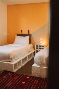 瓦迪穆萨Nomads Hotel Petra的橙色墙壁客房的两张床