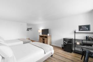 韦斯特波特Silver Sands Motel的配有两张床铺、一张桌子和一台电视机的客房