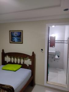 安格拉杜斯雷斯Hospedagem da Val的一间卧室配有一张带绿色枕头和镜子的床