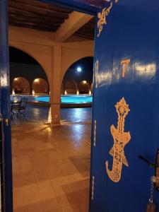 梅尔祖卡阿里摩洛哥传统庭院住宅酒店 的游泳池旁一扇带蜥 ⁇ 的大门