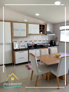 安格拉杜斯雷斯Angra Hostel 147的厨房配有木桌和白色橱柜。