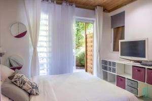 德赛Magnifique et spacieux T2 proche de la plage - La Kiss House的一间卧室设有一张床、一台电视和一个窗口。