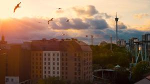 哥德堡Liseberg Grand Curiosa Hotel的鸟群飞过城市的一座建筑物