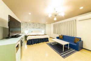 天理市Koriyama Flower Style的一间卧室配有一张床和一张蓝色的沙发