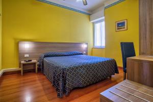 文蒂米利亚卡利普索酒店 的一间卧室配有一张带蓝色床罩和黄色墙壁的床。