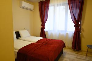 索非亚Hotel Leda的一间卧室配有床和红色窗帘的窗户