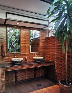 曼谷TAVEE Guesthouse的浴室设有两个水槽和棕榈树。