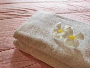 曼谷TAVEE Guesthouse的床上的毛巾,带白色花
