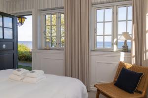 阿灵厄Allinge Badehotel的一间卧室配有一张床、一把椅子和窗户。