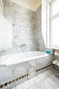 维也纳普利马维拉酒店的白色的浴室设有浴缸和窗户。